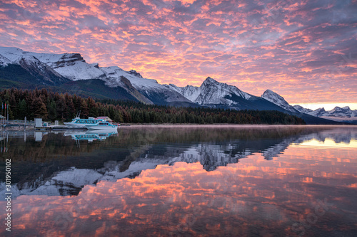Canadian rockies with commercial dock and colorful altocumulus clouds reflections on Maligne lake photo