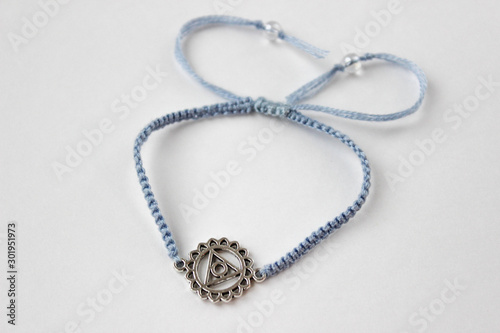 blue braded bracelet with chakra (vishuddha) on white background