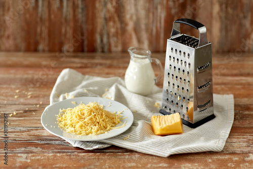 Obraz na płótnie food, cooking and eating concept - close up of grated cheese, grater and jug of