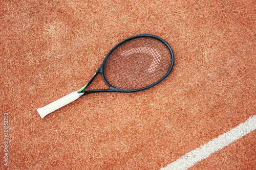 Tennis racket on brown court © Annatamila