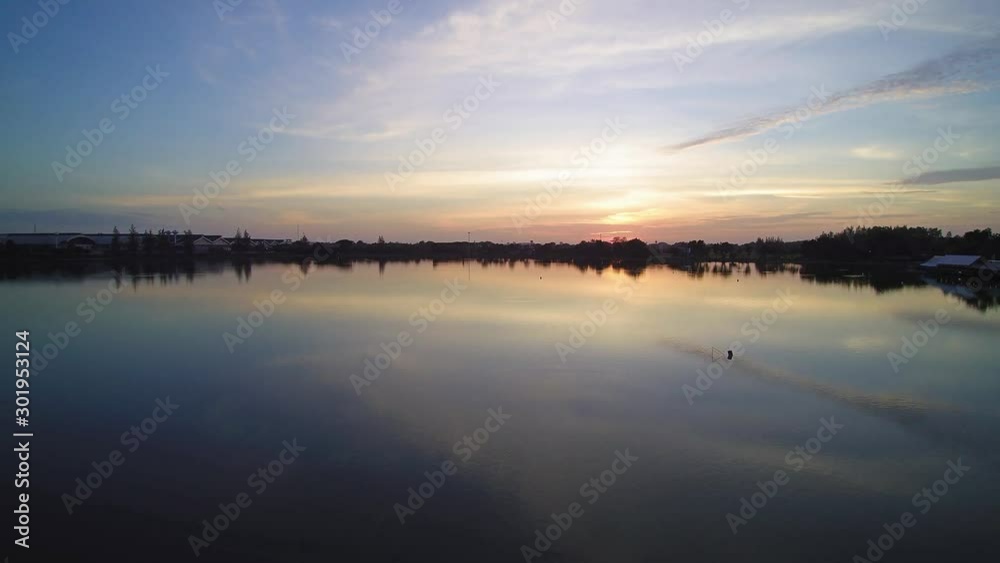 Vdo. Aerial view evening above reservoir around with green tree and yellow sun ling in cloudy sky background, sunset at Krajub reservoir, Nong Kob, Ban Pong, Ratchaburi, Thailand. Vdo. Aerial view evening above reservoir around with green tree and yellow sun ling in cloudy sky background, sunset at Krajub reservoir, Nong Kob, Ban Pong, Ratchaburi, Thailand.