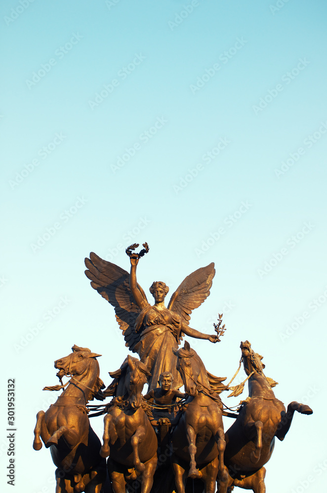 Nike, the winged goddess of victory, riding a bronze quadriga, a chariot of  four rearing horses,