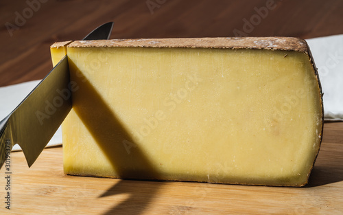 Knife cutting a piece of Comte a famous French cheese photo