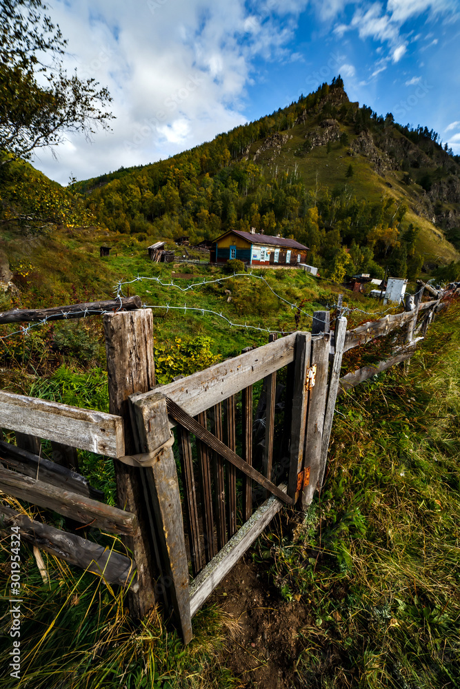 Old Russian village in Siberian woods with wooden gate and fence