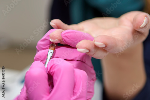    manicurist in pink gloves processes the nails of an adult client using a variety of equipment. Manicure. Beauty shop. Gloved hands take care of the nails of the hands. Procedures.