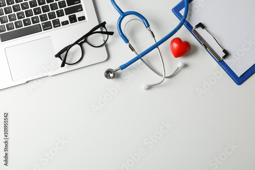 Stethoscope, laptop, tablet, pen and heart on white background, space for text