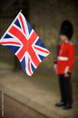 British Union Jack flag flying in front of unrecognizable royal guard soldier on the street in London, UK