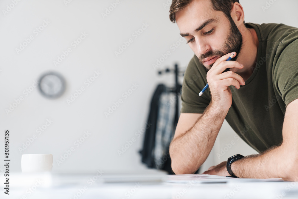 Image of focused caucasian man reading documents and making notes Image of focused caucasian man reading documents and making notes