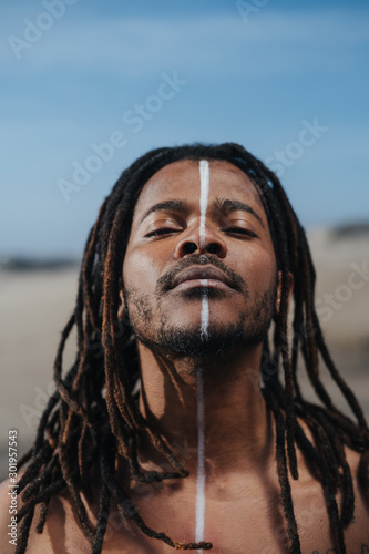 Outdoor emotional Fashion Portrait of African man wearing long dreadlocks and fancy makeup white face paint