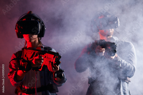 VR gamers with headset, goggles, wearing special equipment with digital devices stand in smoky space