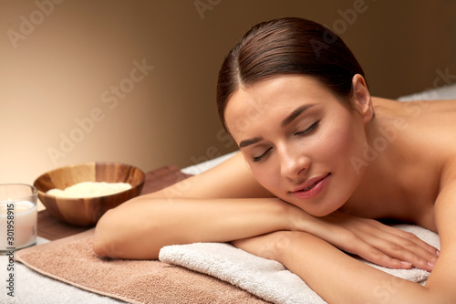 wellness  beauty and relaxation concept - young woman lying at spa or massage parlor