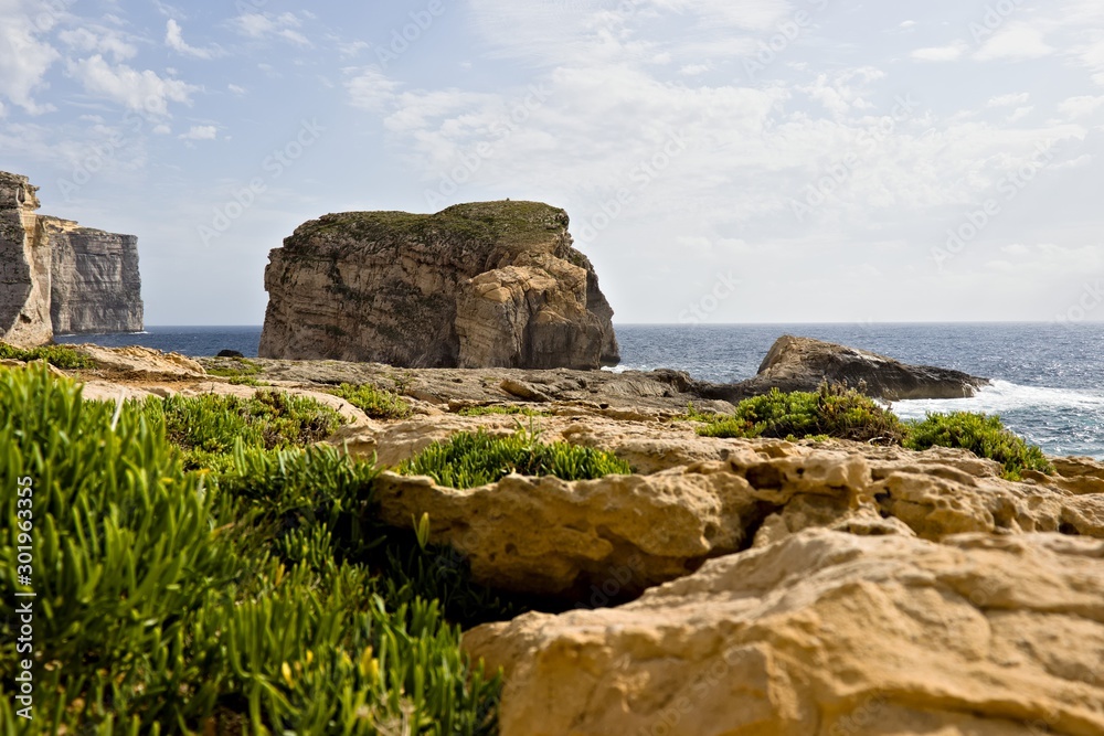 Scenic view of cliffs, fungus rock and blue ocean at dweira bay in gozo.