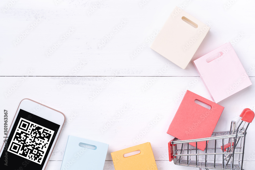 Abstract online shopping, mobile payment with QR code design concept element, colorful cart, paper bag on wooden table background, top view, flat lay Abstract online shopping, mobile payment with QR code design concept element, colorful cart, paper bag on wooden table background, top view, flat lay