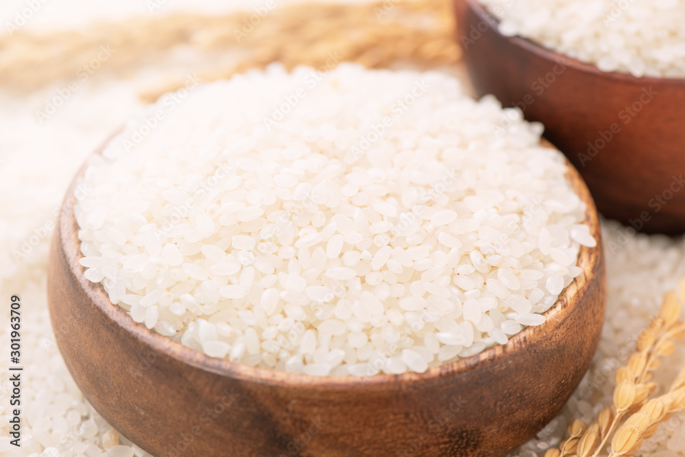 Raw white polished milled edible rice crop on white background in brown bowl, organic agriculture design concept. Staple food of Asia, close up. Raw white polished milled edible rice crop on white background in brown bowl, organic agriculture design concept. Staple food of Asia, close up.