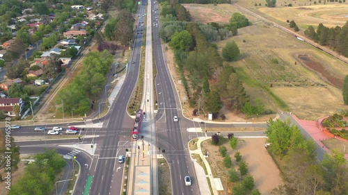 Aerial drone view of a Canberra light rail tram travelling along the Federal Highway during one of its commutes from Gungahlin to Canberra city in the early morning on a sunny day photo