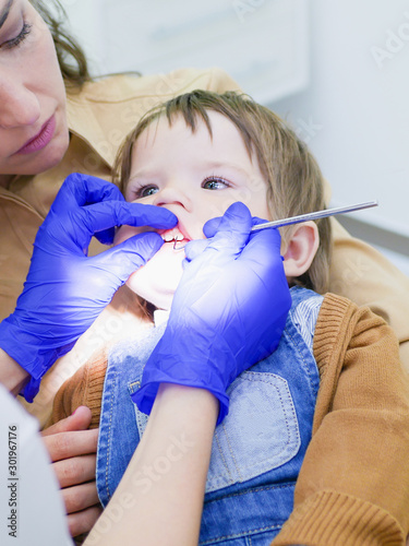 Examination of teeth in a child. Maternal care for a childs healthy teeth. Pediatric Dentist Examining A Little Boys Teeth In The Dentists