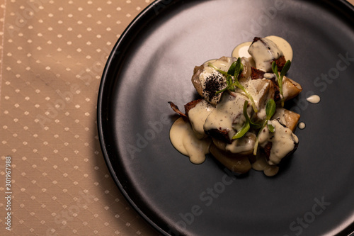 Deer heart with porcini mushrooms and sauce on a black plate. photo