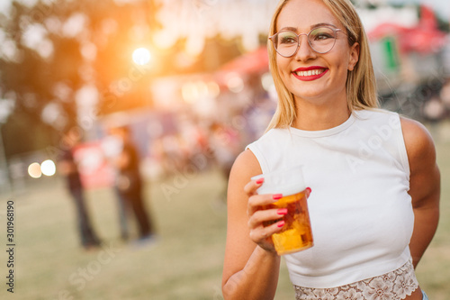 Woman holding beer and listening music at festival