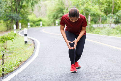 Woman running hurt at her knee between run training.