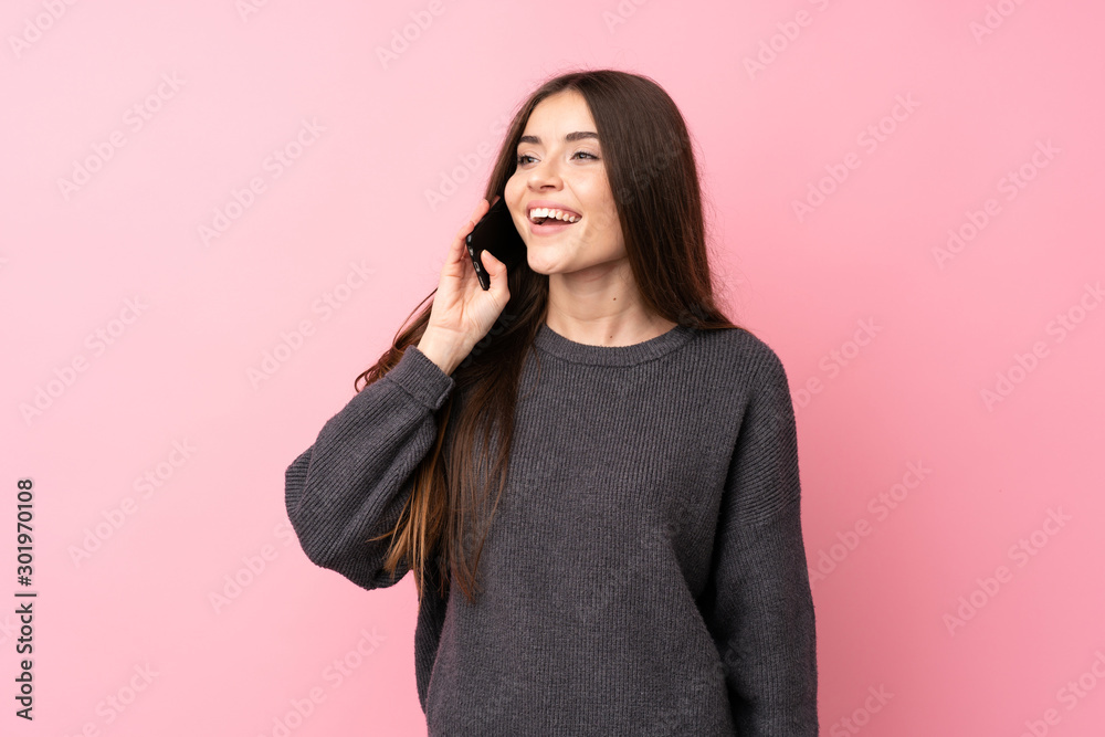 Young woman over isolated pink background keeping a conversation with the mobile phone Young woman over isolated pink background keeping a conversation with the mobile phone