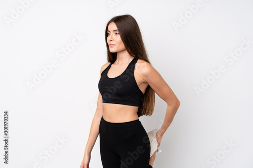 Young sport woman over isolated white background stretching leg