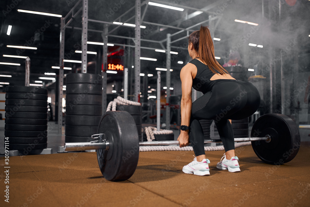 Pretty attractive female training in gym doing exercises with barbell powerlift, young model working with body in fitness hall, healthy lifestyle and diet concept Pretty attractive female training in gym doing exercises with barbell powerlift, young model working with body in fitness hall, healthy lifestyle and diet concept