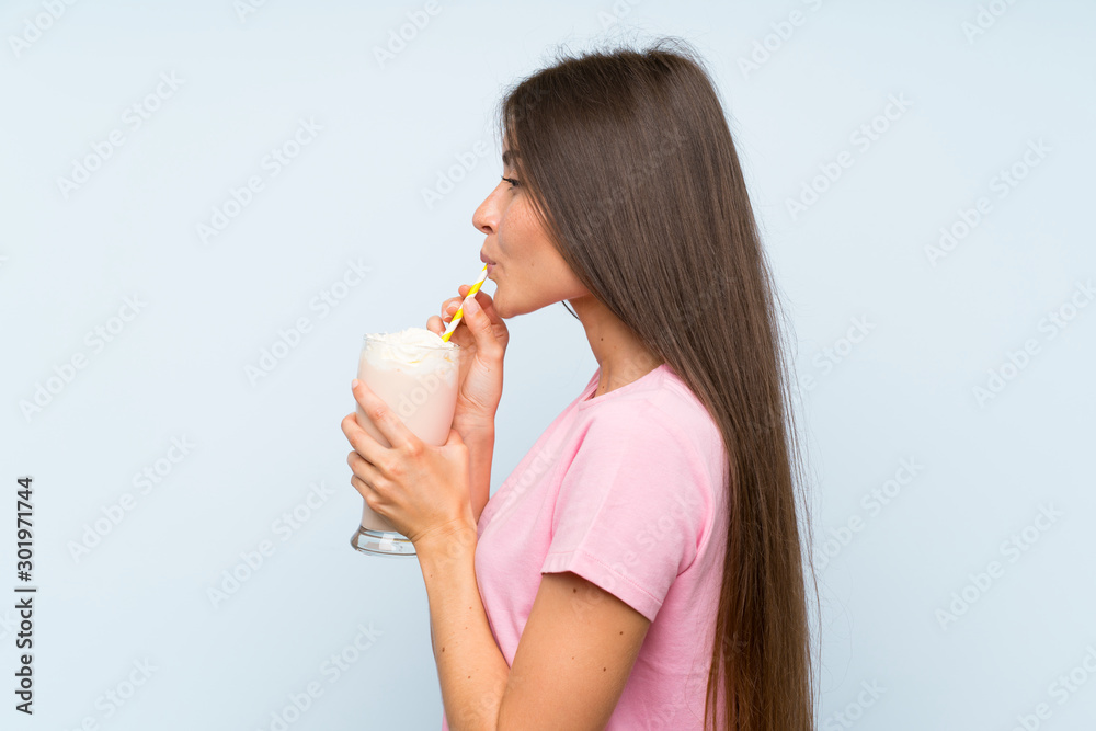 Young woman with strawberry milkshake over isolated blue background Young woman with strawberry milkshake over isolated blue background