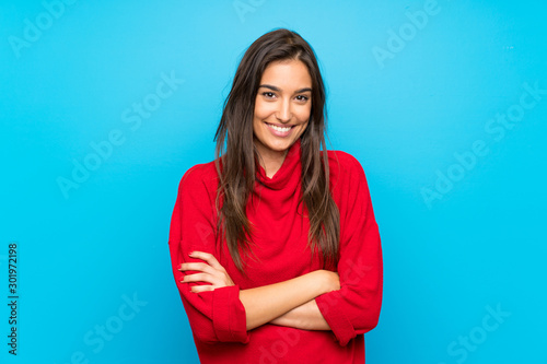 Fotografia Young woman with red sweater over isolated blue background laughing