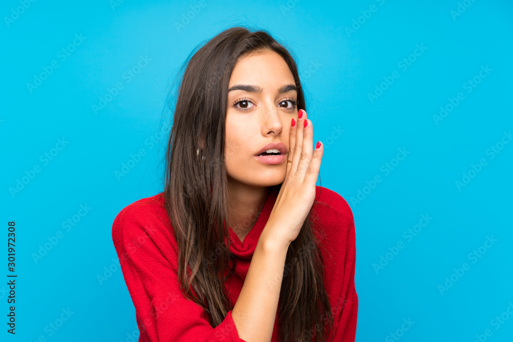 Young woman with red sweater over isolated blue background whispering something Young woman with red sweater over isolated blue background whispering something