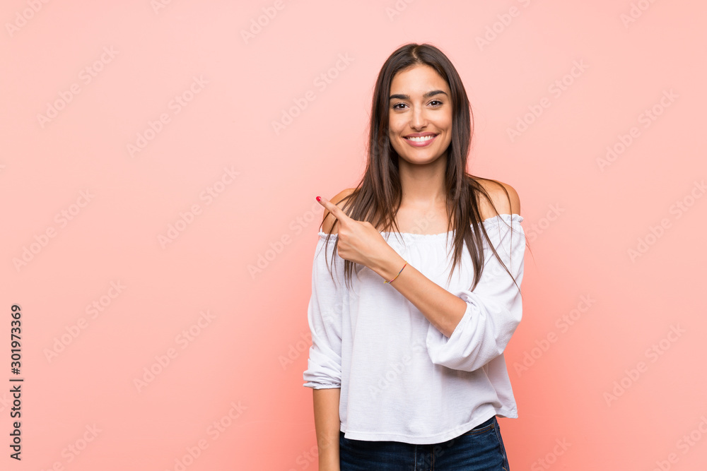 Young woman over isolated pink background pointing to the side to present a product Young woman over isolated pink background pointing to the side to present a product