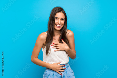 Young woman over isolated blue background smiling a lot © luismolinero