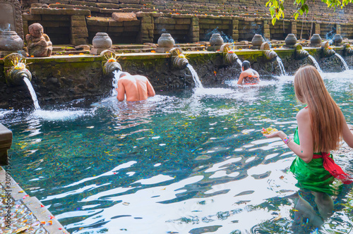 Young girl is praying in holy spring water of sacred pool - Pura Tirtha Empul Temple, Indonesia photo