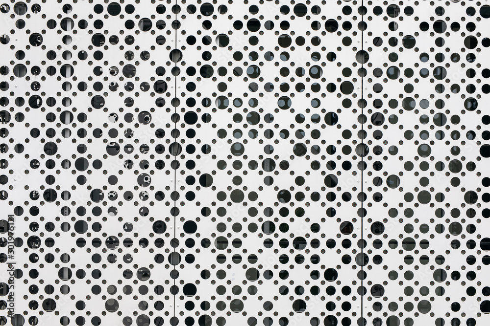 Black and white random dots pattern. Porous abstract white background with circles of different diameters. White metal mesh texture with uneven holes.