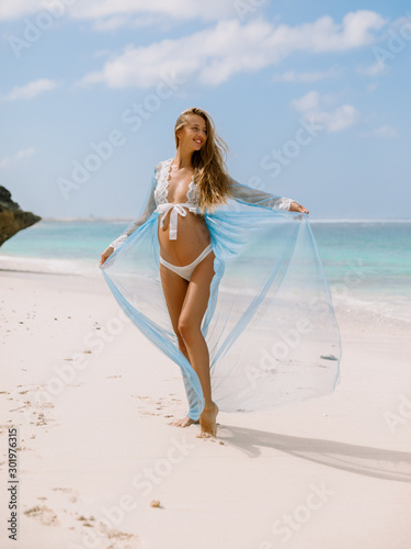 Young pregnant woman in dress expecting baby, posing at tropical beach © artifirsov