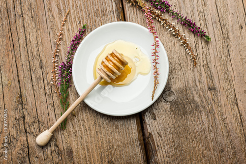 Fototapeta Naklejka Na Ścianę i Meble -  honey dipper on saucer with honey on wooden table with flowers