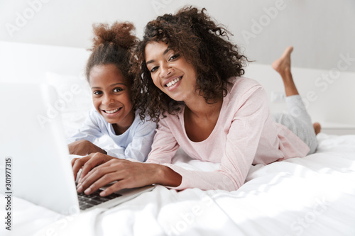 Smiling young mother and her little daughter wearing pajamas