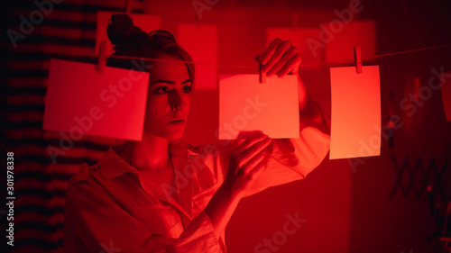 photographer on work, amateur, hobbyist or professional Young girl developing photos in a dark room. Retro style photography