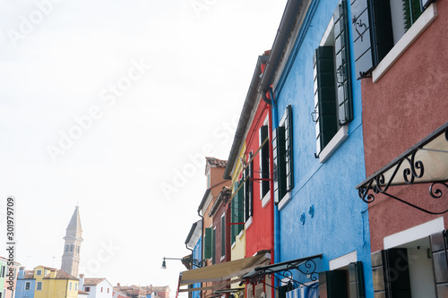 Windows in blue and red wall of the houses. View with bell tower. Background, travel photo. Murano island. Italy. Europe.