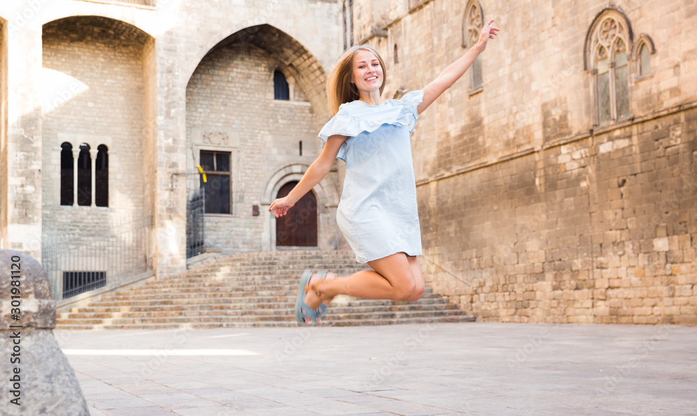 Girl jumping up against stone building