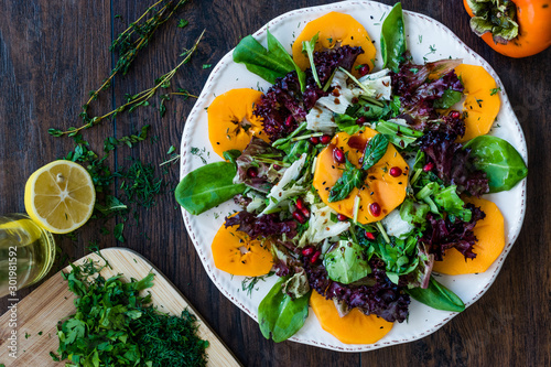 Persimmon Fruit Salad with Pomegranate, Lollo Rosso Lettuce, Rocket Arugula or Rucola and Mint Leaves.