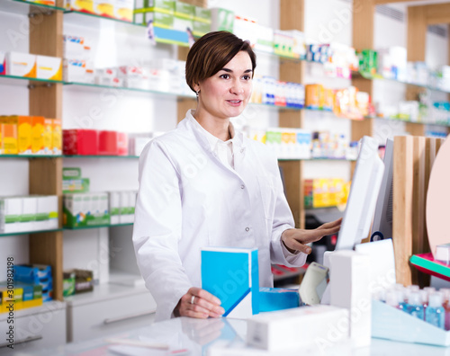 female pharmacist offering assistance at counter in pharmacy