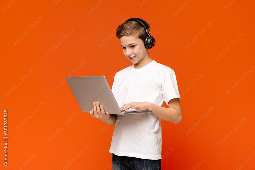 Teenage boy in headphones playing video game on laptop Teenage boy in headphones playing video game on laptop