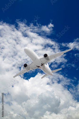 white passenger plane flies against backdrop of beautiful white clouds on blue sky