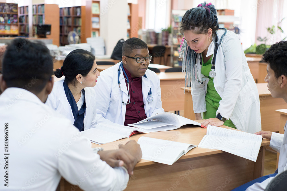Fototapeta premium doctor of medicine. A group of young people of mixed race, sitting at a table in the office of the hospital, read medical literature