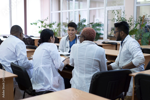 group of young doctors  mixed race  sitting at the table in the hospital  discussing medicine