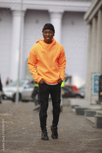 Handsome African man model wearing bright orange hoodie in city © antgor