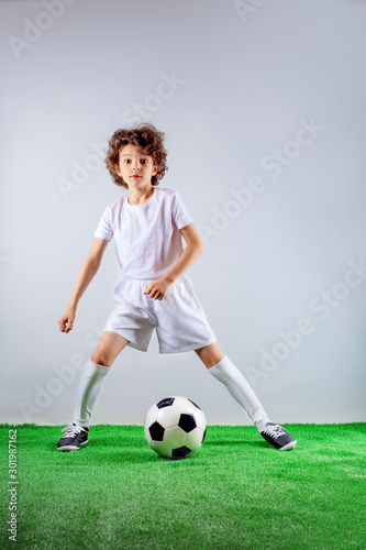 Photo of smiling little boy with a soccer ball - posing in studio