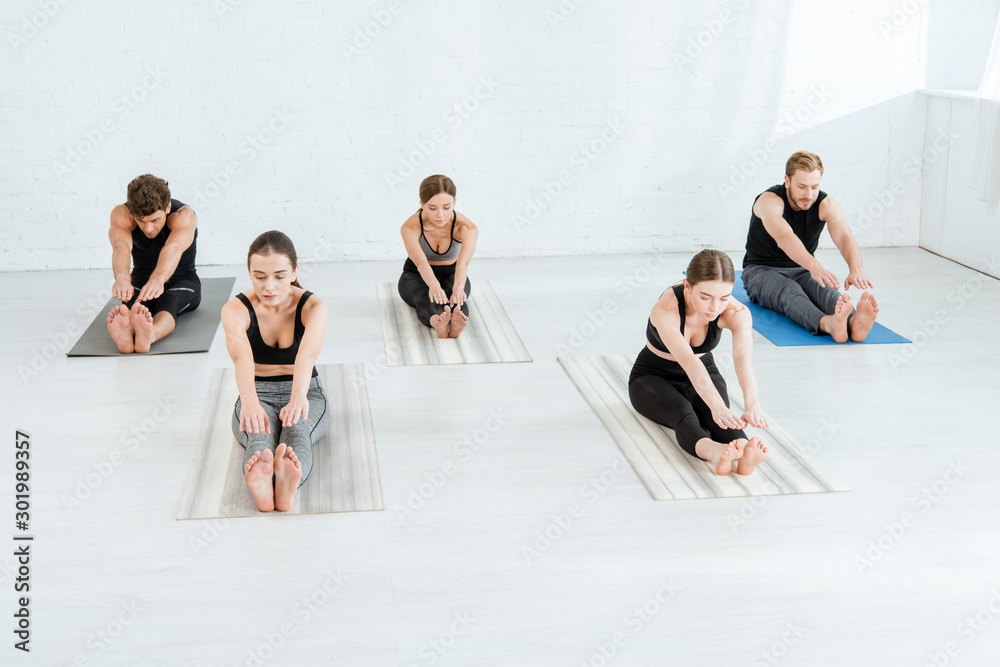 Naklejka premium five young people practicing yoga in forward bend pose