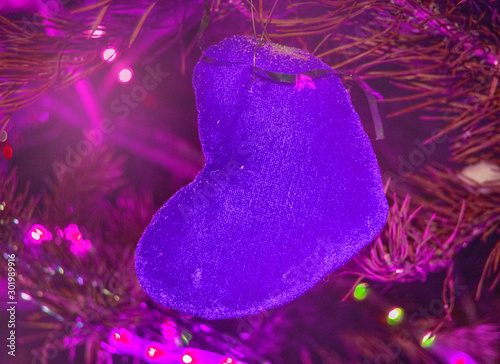 Christmas background-purple heart of canvas on a background of fir branches with lilac backlight, futuristic neon holiday background photo