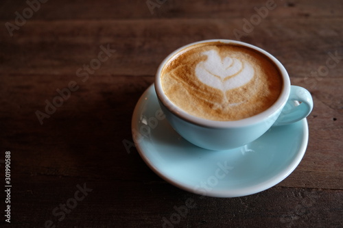 Cappuccino or latte with frothy foam, blue coffee cup top on wooden coffee shop background